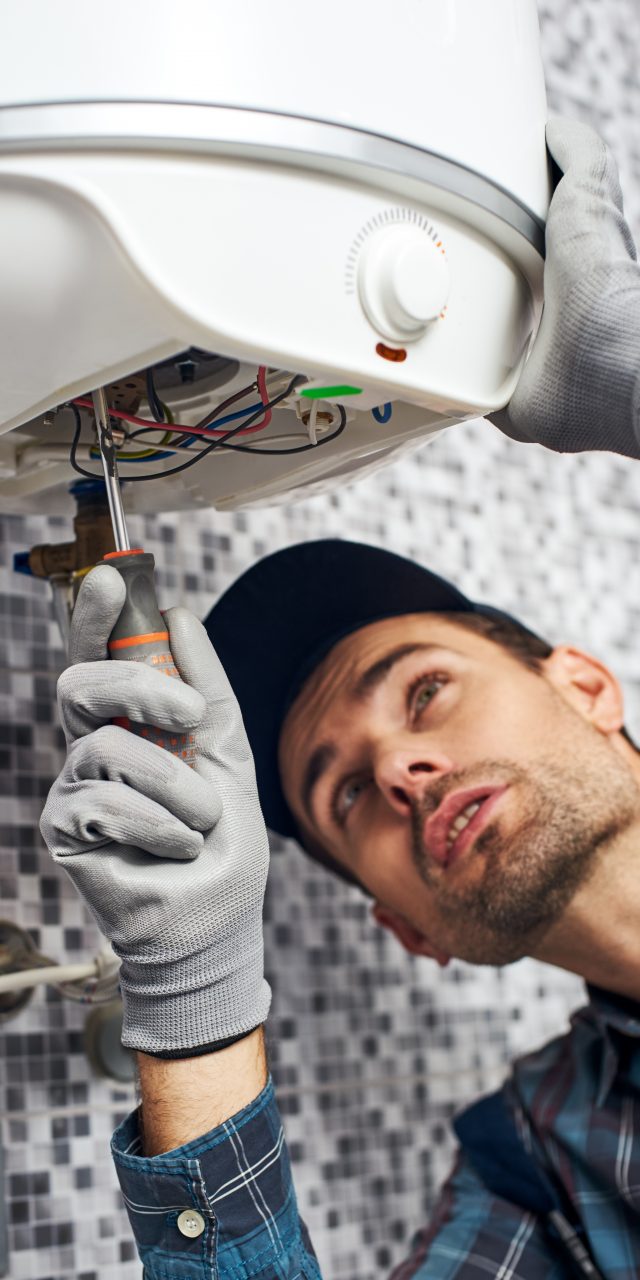 Set up boiler. Worker set up electric heating boiler at home. Close-up of young handyman